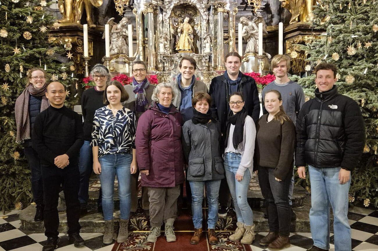 Eine Gruppe von dreizehn Personen posiert für ein Foto in einer reich verzierten Kirche mit Goldverzierungen.